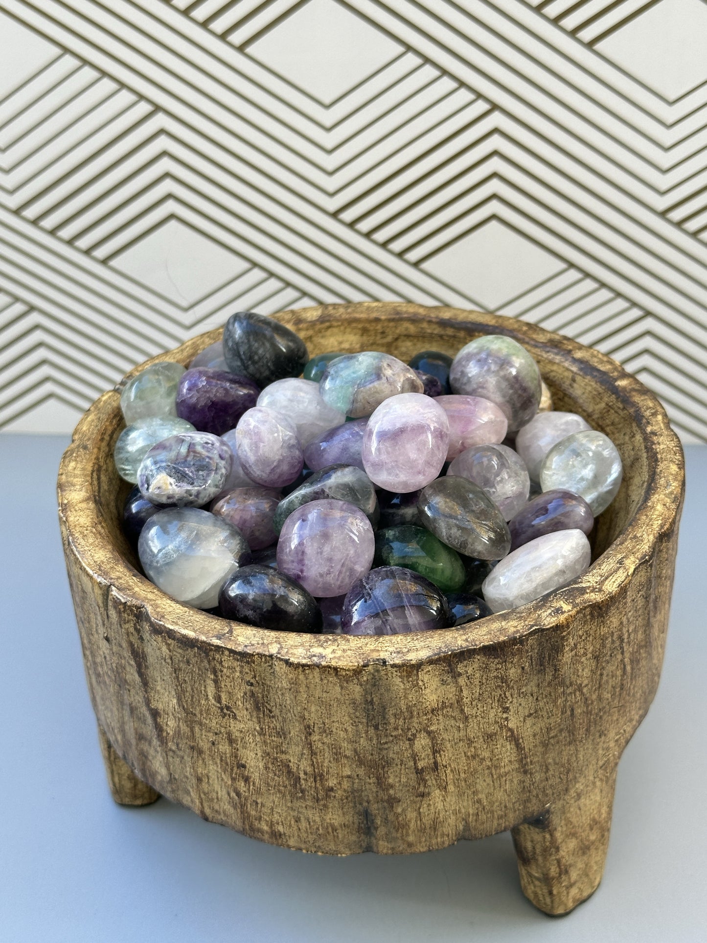 A serene arrangement of Rainbow Fluorite stones in a brown bowl, with vibrant colors symbolizing focus, balance, and shielding energy